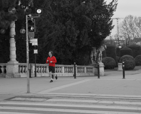 Jogger nähe Volkstheather. Schwarz-weiß-Bild mit Jacke vom Jogger in rot.