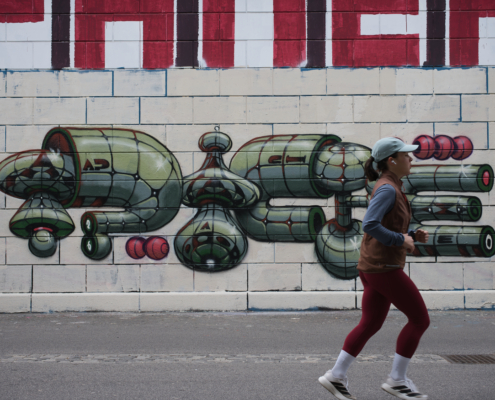 Joggerin laufend vor Grafiti. Farben von beiden Motiven harmonisch