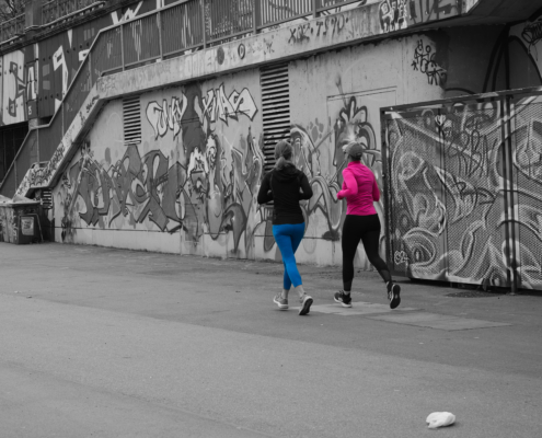 schwarz-weiß-Bild mit 2 Joggerinen (eine mit schwarzen Oberteil und Blauer Hose, andere mit rosa Oberteil und schwarzer Hose)