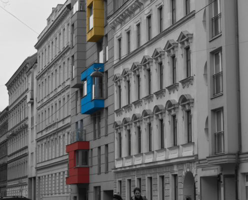 Schwarz-weiß-Bild mit rotem, blauen und gelben herausstehendes Element im Haus.