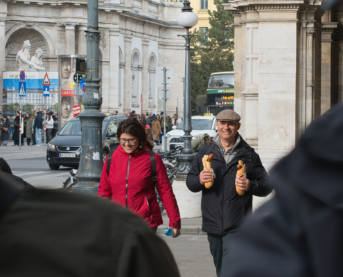 Vor der Albertina. Mann mit 2 Hotdogs grinsend