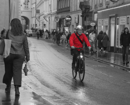 Schwarz-Weiß Bild mit Herrn am Fahrrad mit Roter Jacke